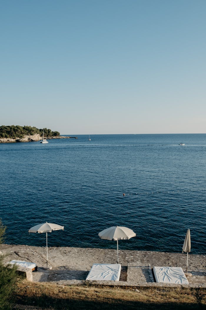 Calm beach scene with sun umbrellas and loungers on a Croatian coastline.